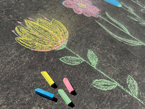 Multicolor flowers and colored chalk &ndash; a child's chalk drawing on the asphalt