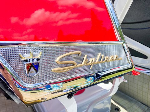 Auburn WA USA, July 4th, 2026: Close-up of a chrome Skyliner script emblem and Ford crest on a vintage red and white car