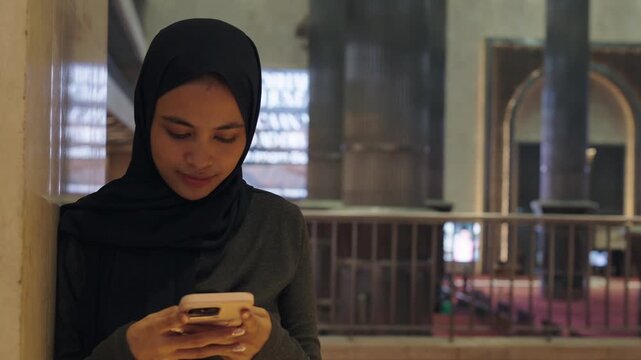 Muslim woman using smartphone inside a mosque