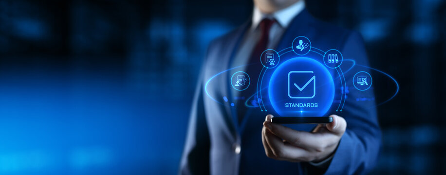 Businessman Holding smartphone with Standards Icons on Screen. Quality Management concept