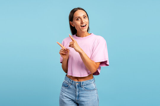 Young woman smiling pointing fingers left advertisement