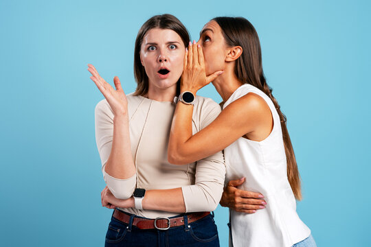 Woman whispering secret gossip causing friend's surprise