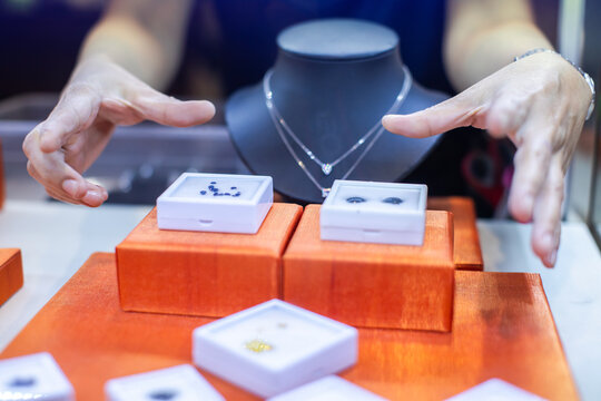 Selective focus to Jeweler presenting fine gemstones and luxury jewelry display in retail store counter