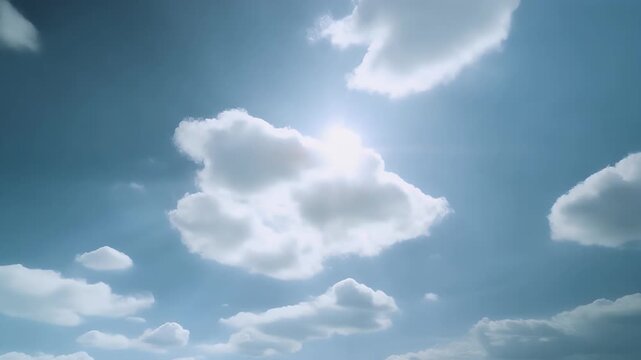 Sunlight filtering through fluffy clouds in a clear blue sky.
