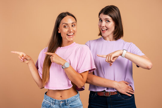 Young women pointing to empty space advertising something