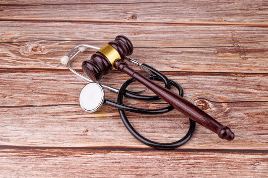 Direct angle of a mahogany judge gavel and stethoscope on rustic wood