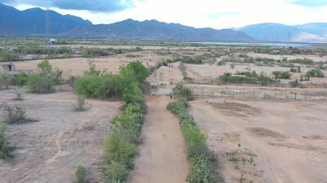 Aerial drone view of photographers capturing Cham women in traditional dress herding sheep in An Hoa Village, Xuan Hai, Khanh Hoa, Vietnam, showcasing rural life and cultural heritage.