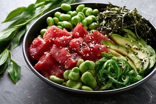 Gourmet ahi tuna poke bowl with edamame avocado and seaweed on slate with sharp focus