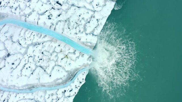 Aerial view of a glacier waterfall, caused by the melting of the arctic ice, a consequence of climate change.