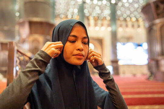 Muslim woman adjusting hijab preparing for prayer inside mosque