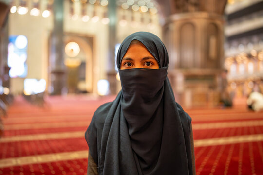 Muslim woman wearing niqab standing inside mosque