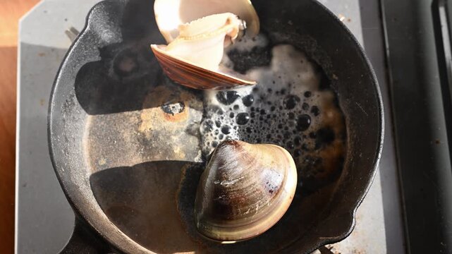 網焼きでぐつぐつと沸騰する醤油と湯気が立つ大粒のハマグリ