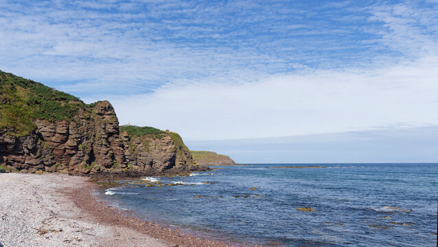 The Gently shelving Shingle Beach at Pennan on the Coast of the Moray Firth in North Scotland with the tide slowly retreating.
