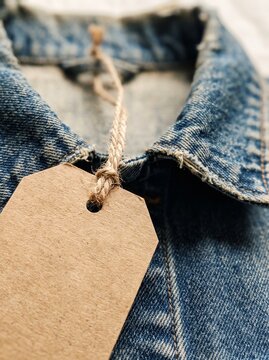 Blank brown kraft paper price tag attached with twine on vintage denim jacket collar mockup