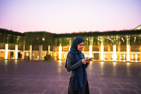 Muslim woman wearing hijab using smartphone in urban area