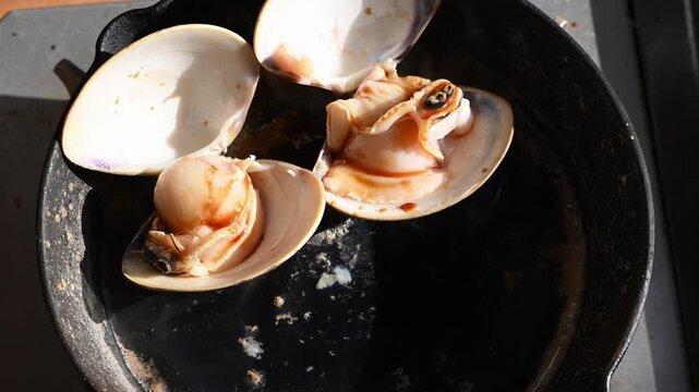 網焼きでぐつぐつと沸騰する醤油と湯気が立つ大粒のハマグリ