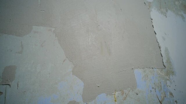 Professional construction worker applying plaster or putty to a damaged wall with a trowel during renovation, leveling the surface for a smooth finish before painting and home improvement