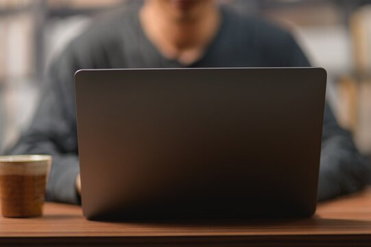 Person Working on Laptop at Desk with Coffee in a Modern Office Environment