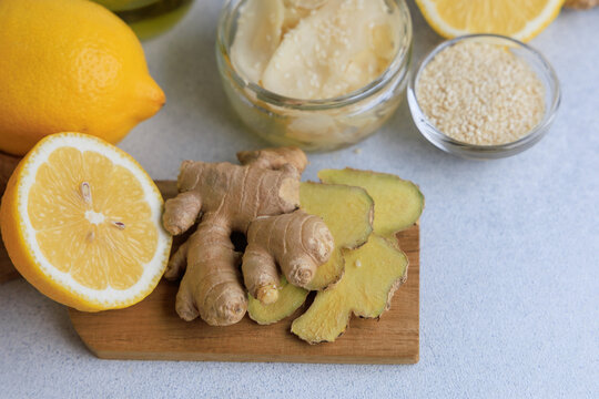 Pickled ginger and ingredients on a wooden board with lemons and sesame seeds in a kitchen setting