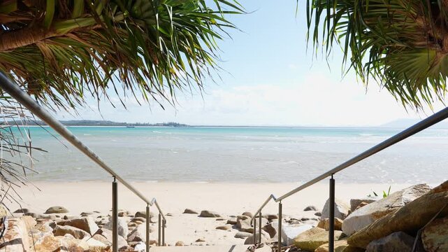 Beach access stairway framed by pandanus palms leading down to the turquoise water of Trial Bay, New South Wales, Australia