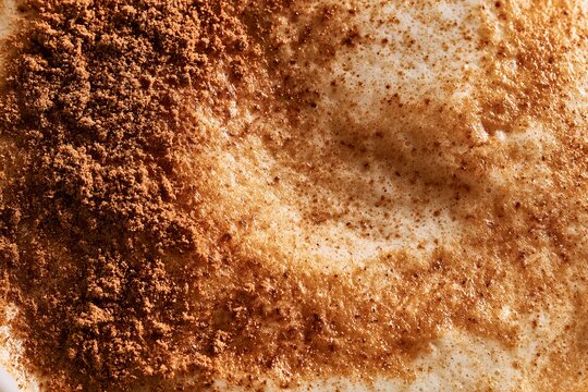 Coffee with cinnamon sprinkled on top served in a cafe setting during morning hours