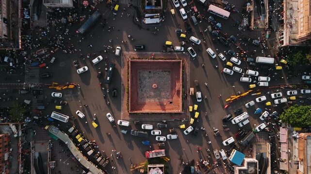 Aerial view of city traffic with cars, rickshaws moving around a square landmark in jaipur, india at sunset