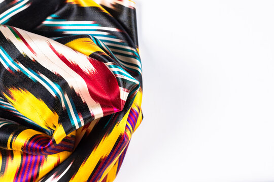 traditional Uzbek adras ikat fabric arranged in flowing folds on a white background, textile, fashion, interior and cultural Central Asia travelling concept, vertical