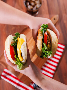 Two delicious homemade cheeseburger stacked together featuring juicy meat beef pork patty melted cheese fresh lettuce tomato holding by hand on wooden background classic burger fast food advertising.