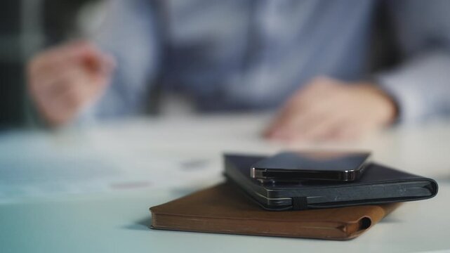 Close-up of office desk with phone and planner as businessman signs papers