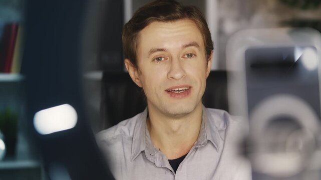 Young man records business video blog on phone in office, giving business advice