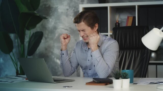 Young businessman reads bad news email on laptop, angry about failed contract