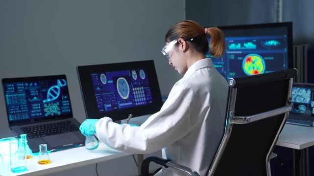 Female medicine doctor, physician or practitioner in lab room writing on blank notebook and work on laptop computer, analysis the blood test examination results and medication usage.