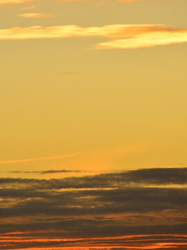 Sunset with very dark stratocumulus clouds and higher, golden altostratus clouds.