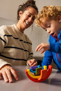 Mother and young son playing with colorful wooden balancing toy, learning and development concept