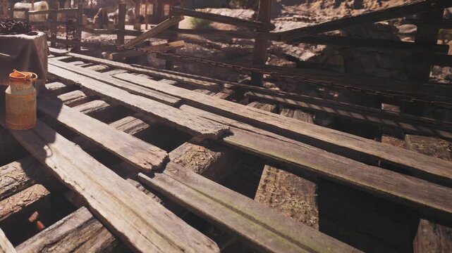 Wooden planks are laid across a bridge at a construction site. The sun casts shadows on the rough surface. Tools and materials are scattered around, indicating work in progress.
