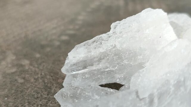 Natural white alum crystal stones on a textured concrete surface. Ideal for natural deodorant, body care, cosmetics, and water purification concepts