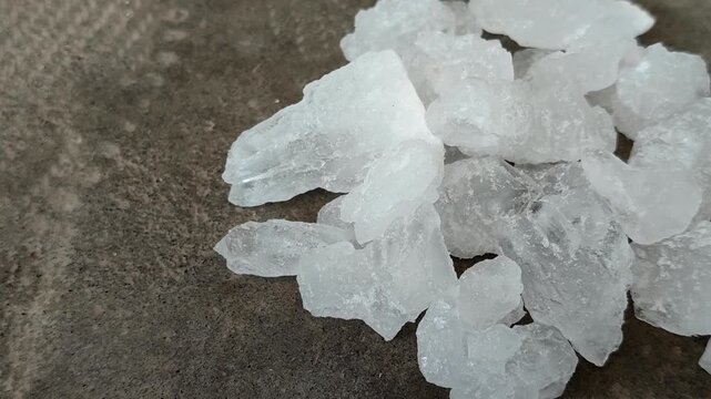 Natural white alum crystal stones on a textured concrete surface. Ideal for natural deodorant, body care, cosmetics, and water purification concepts