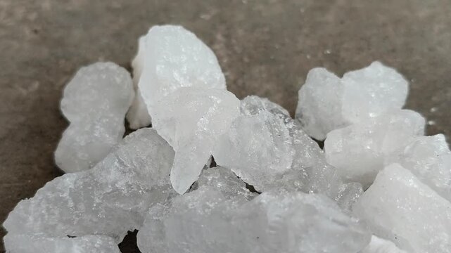 Natural white alum crystal stones on a textured concrete surface. Ideal for natural deodorant, body care, cosmetics, and water purification concepts