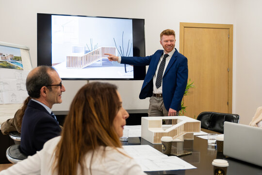 Architect presenting building design model to colleagues during a professional meeting