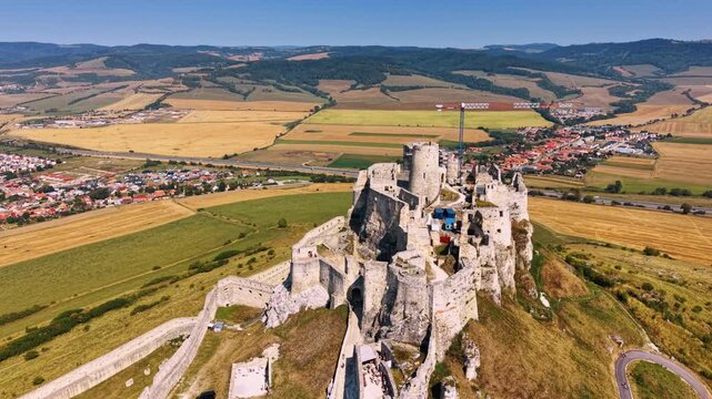 Castle on a hilltop overlooking fields. The castle stands on a hilltop with fields and towns visible in the distance, showing a sunny day and clear skies.