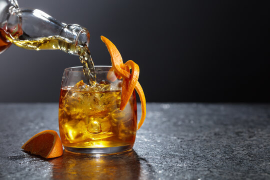 Old-fashioned cocktail in a fogged up glass on a black stone table.