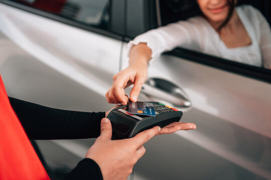 Woman making a contactless payment with a credit card terminal from her car at a gas station