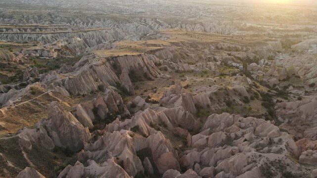 Cinematic aerial drone footage of Cappadocia&rsquo;s spectacular rock formations and fairy chimneys at sunset, bathed in warm golden light, showcasing the unique volcanic landscape of central Turkey.