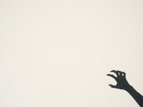 Ominous shadow of a hand reaching out against a stark white background creating a mysterious mood