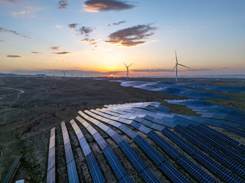 wind turbines and solar panels under sunset sky