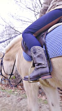 Cowboy riding horse inside manege close up on boots