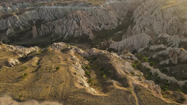 Cinematic aerial drone footage of Cappadocia&rsquo;s spectacular rock formations and fairy chimneys at sunset, bathed in warm golden light, showcasing the unique volcanic landscape of central Turkey.