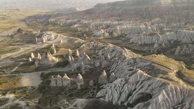 Cinematic aerial drone footage of Cappadocia&rsquo;s spectacular rock formations and fairy chimneys at sunset, bathed in warm golden light, showcasing the unique volcanic landscape of central Turkey.