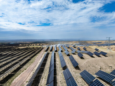 rows of solar panels on dry land under blue sky