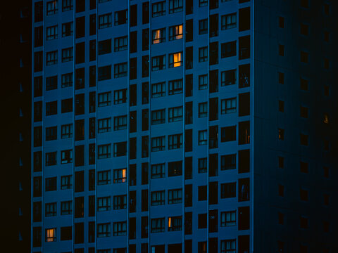Close-Up of Blue-Toned Apartment Facade with Isolated Glowing Windows at Night